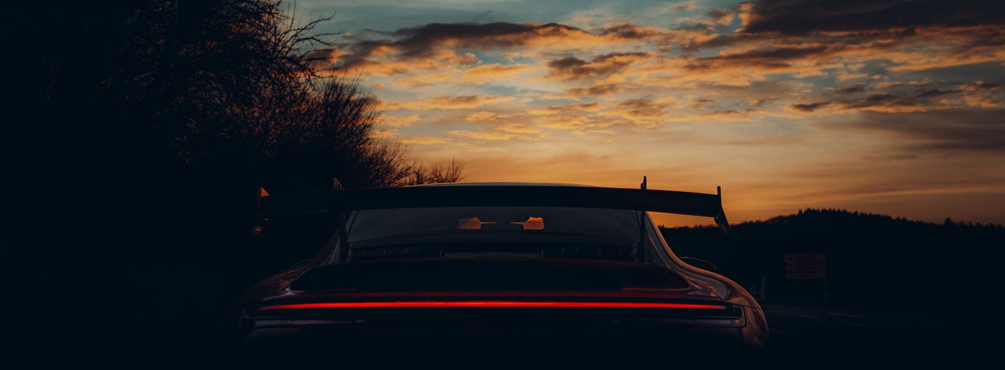Silhouette des Heckflügels eines Porsche 911 GT3 vor dem Abendhimmel.