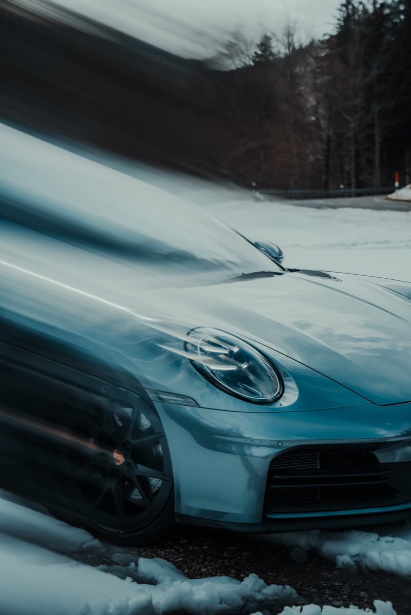 Porsche 911 in Bewegung auf einem verschneiten Alpenpass.