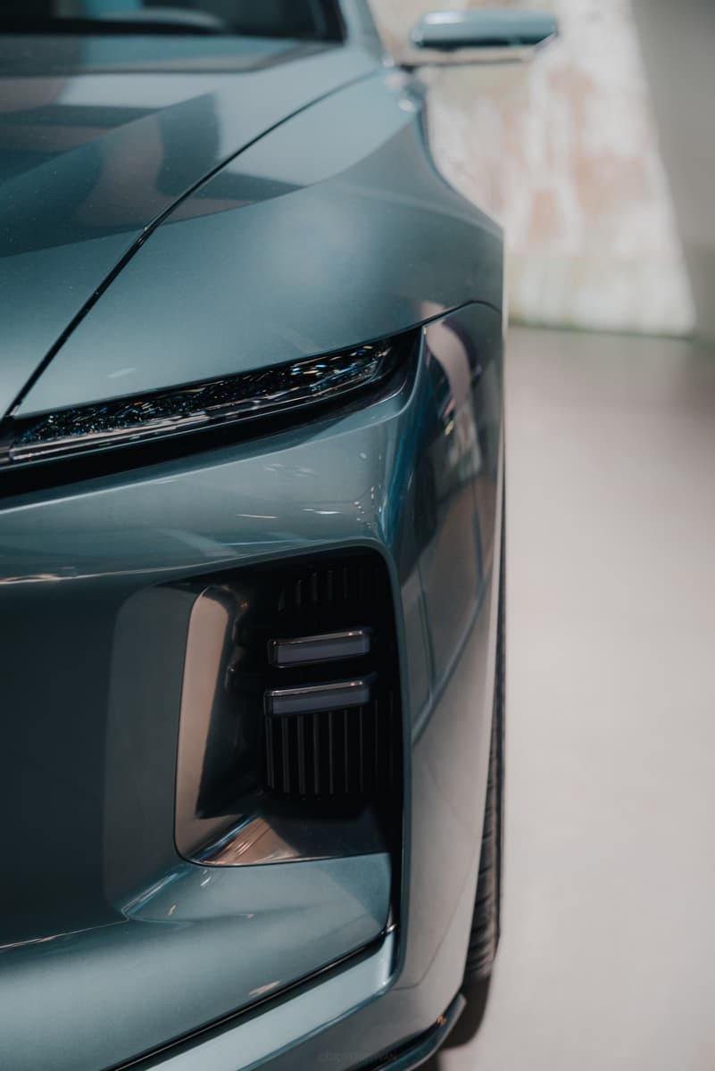 Scheinwerfer und Kühlergrill eines türkisen SUV im Showroom.